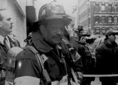 Firefighter in helmet communicating by radio at an urban scene