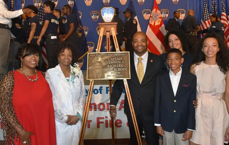 Family poses beside Captain Vernon A Richard High School dedication plaque