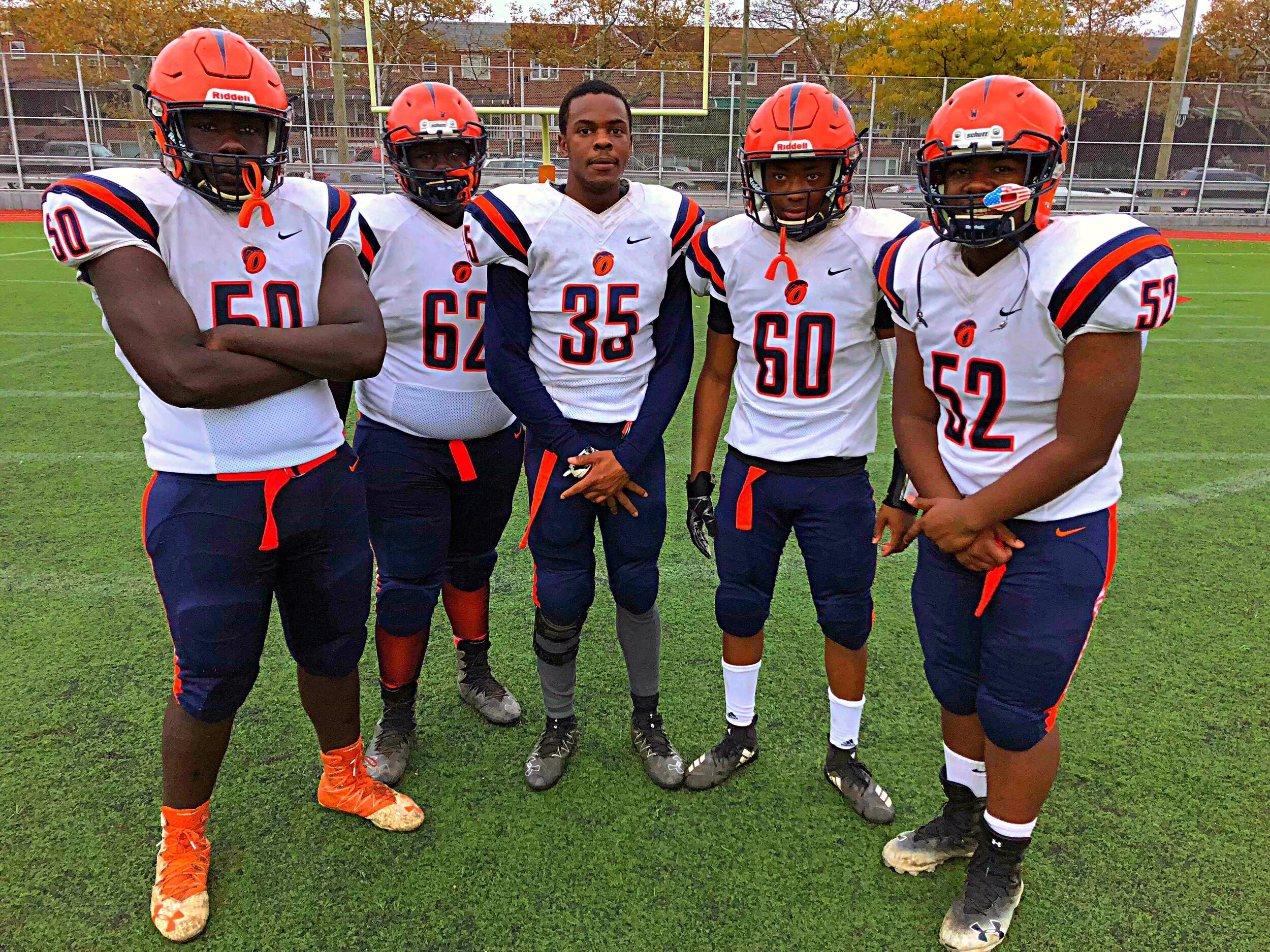 Five high school football players posing together on the field