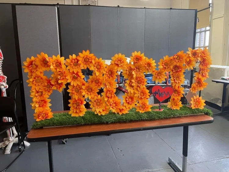 Orange flower letter display spelling PROM on a table