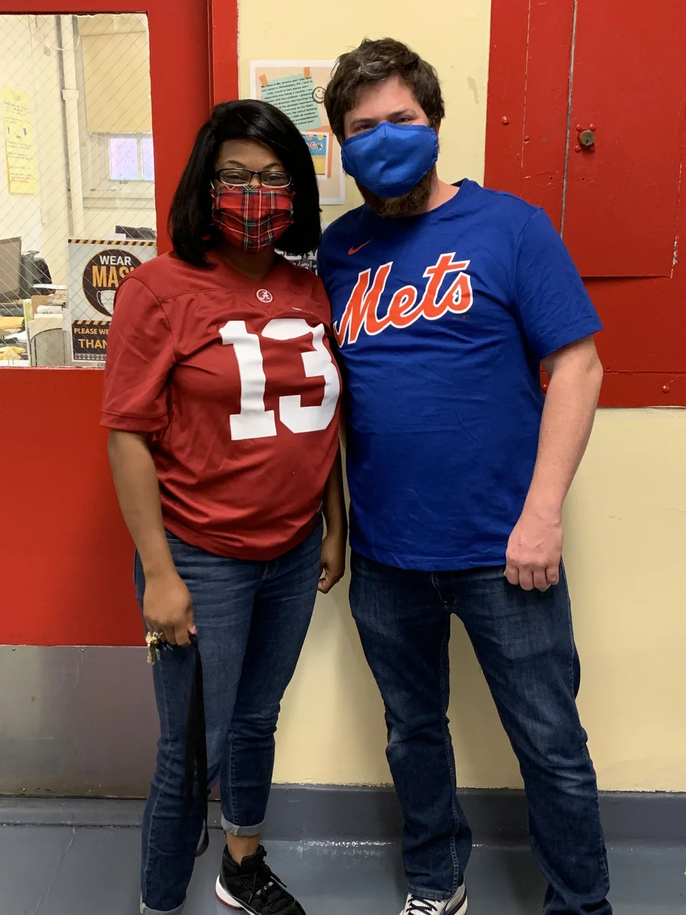 Two masked staff members wearing sports jerseys at school