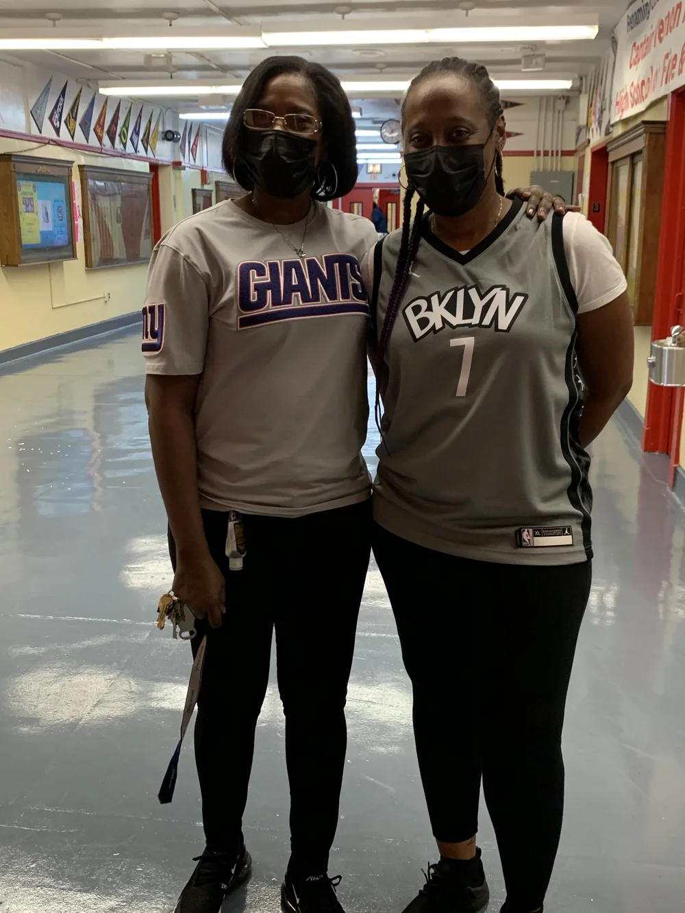 Two staff members wearing sports jerseys in school hallway