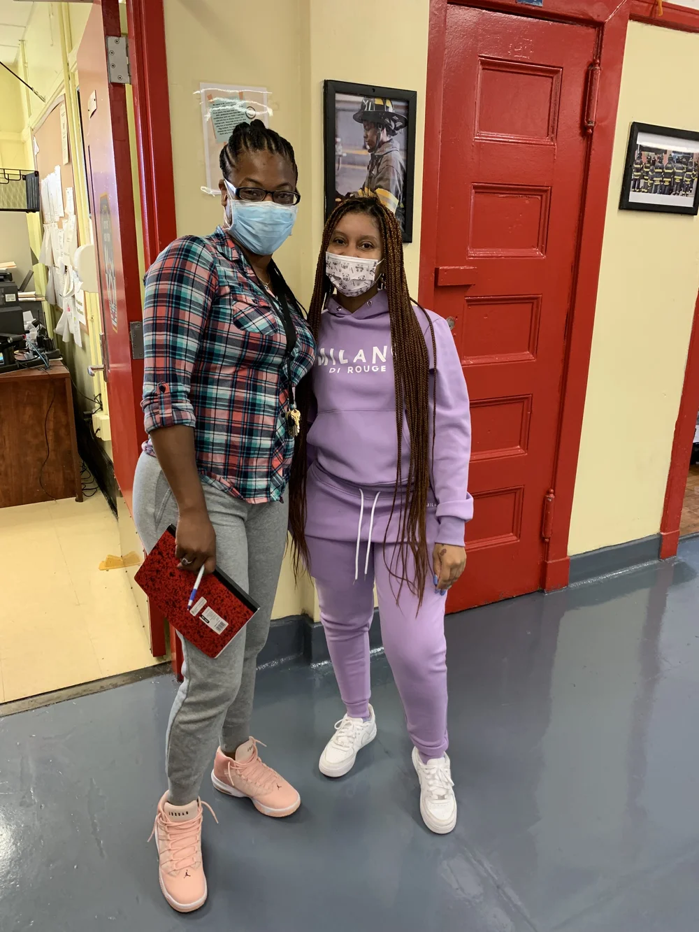 Two masked students posing together in a school hallway