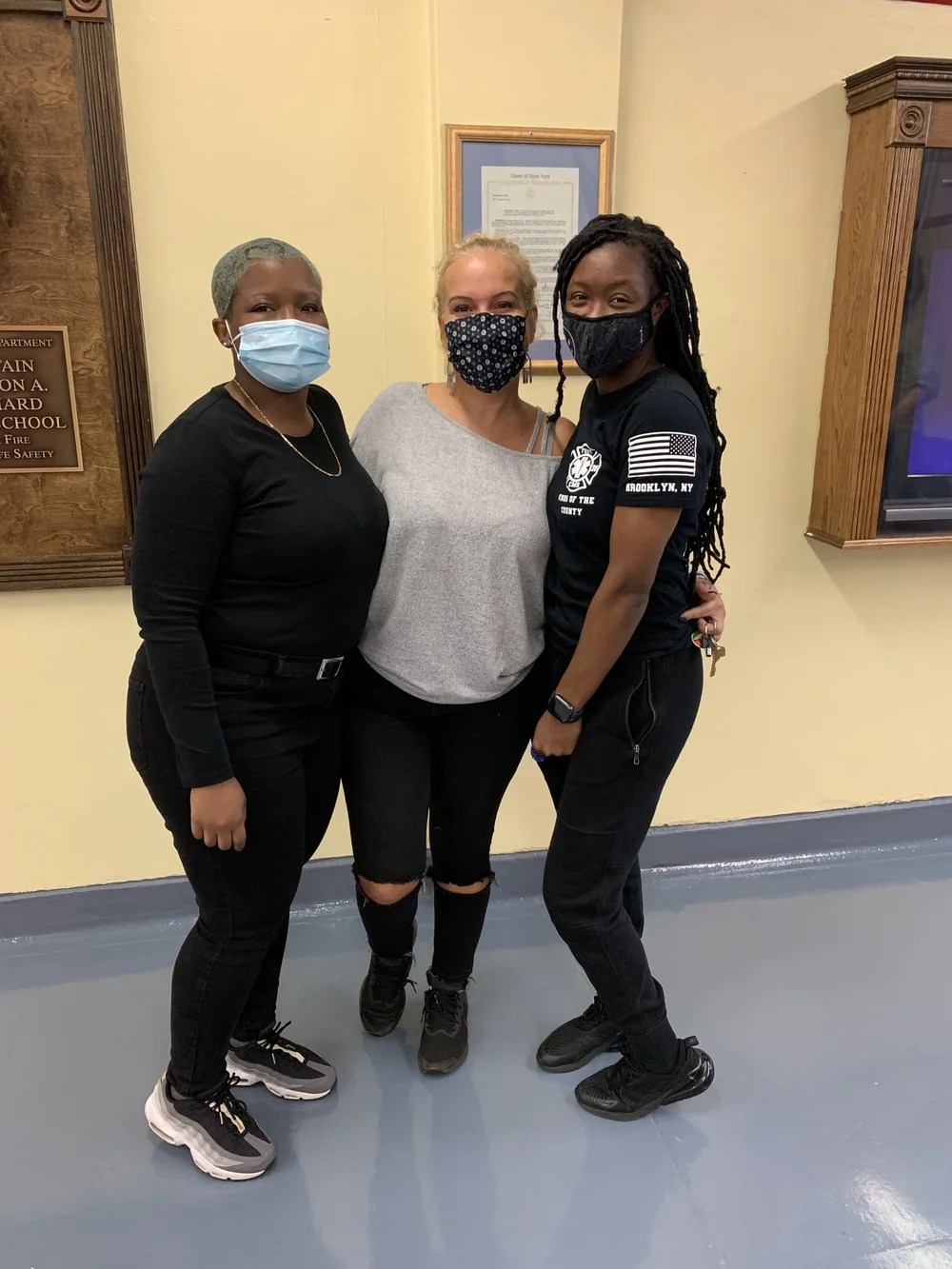 Three masked staff members posing together inside school building