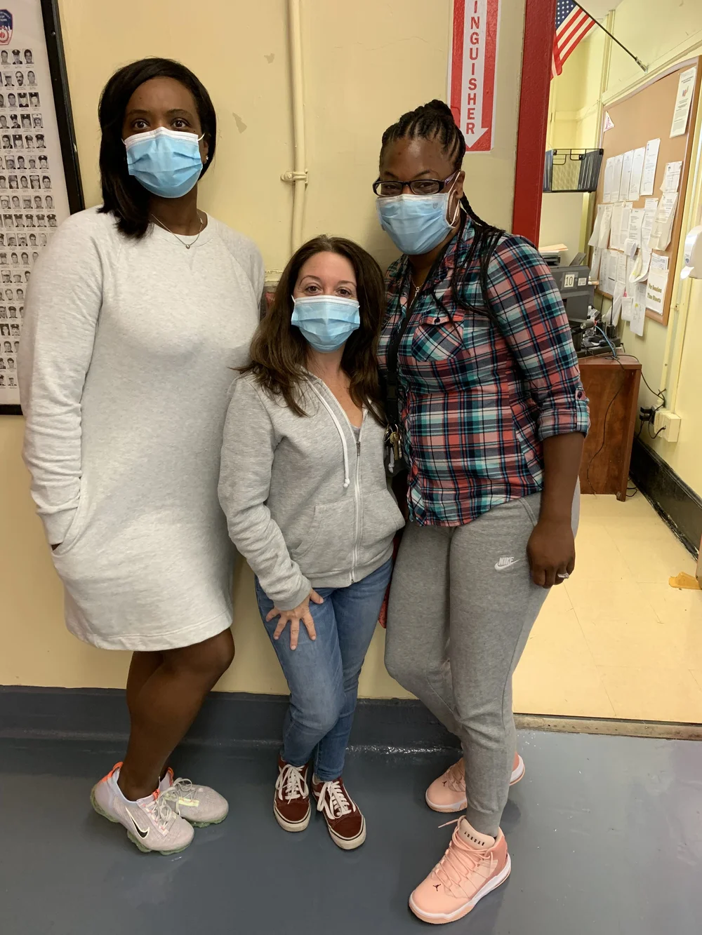 Three school staff members wearing masks inside school building