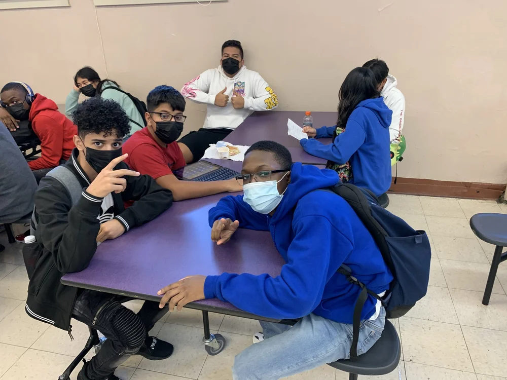 Students wearing masks sitting together at cafeteria tables