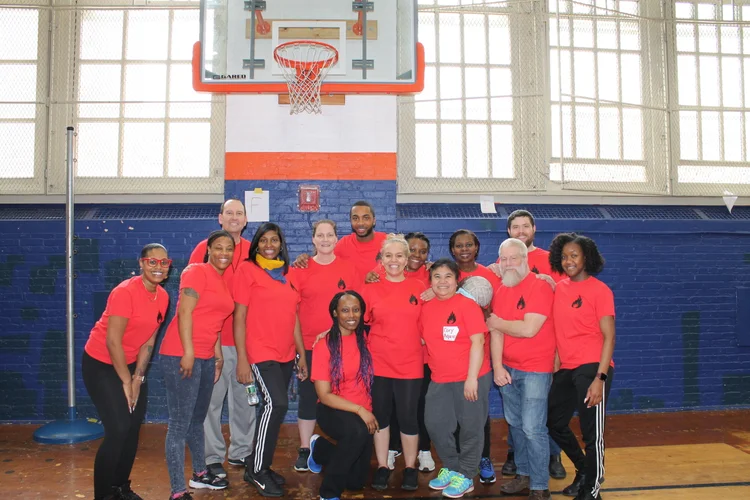 Staff members in matching red shirts posing in school gymnasium