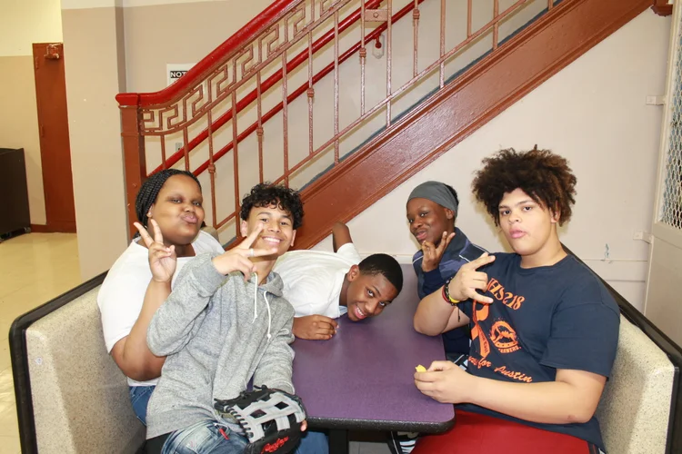 Five middle school students posing together near school staircase