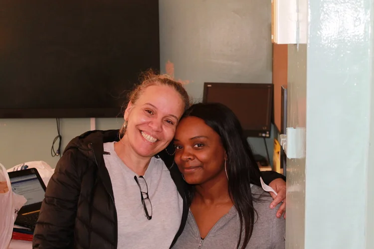 Two staff members smiling together in a school office