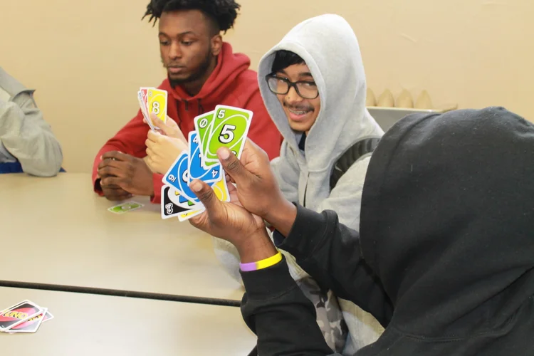 Students playing Uno card game together at a table