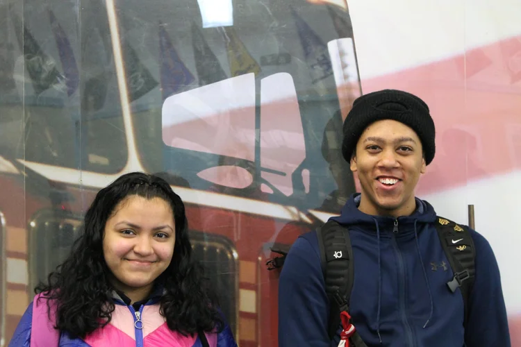 Two smiling students standing in front of a fire truck