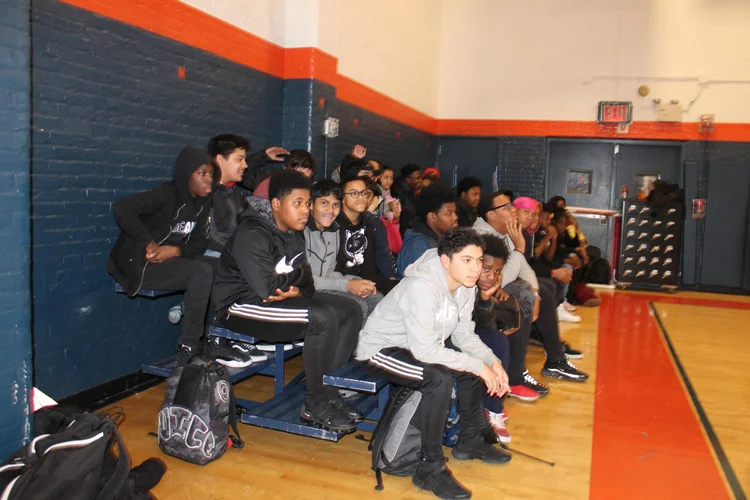 Students seated on gymnasium bleachers during a school assembly