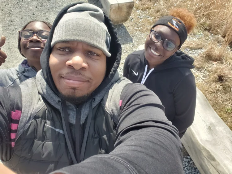 Three students smiling together outdoors on a school trip