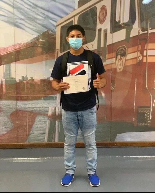 Student wearing mask holding certificate at FDNY High School