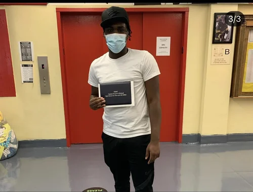 Student holding a tablet displaying an acceptance letter in school hallway