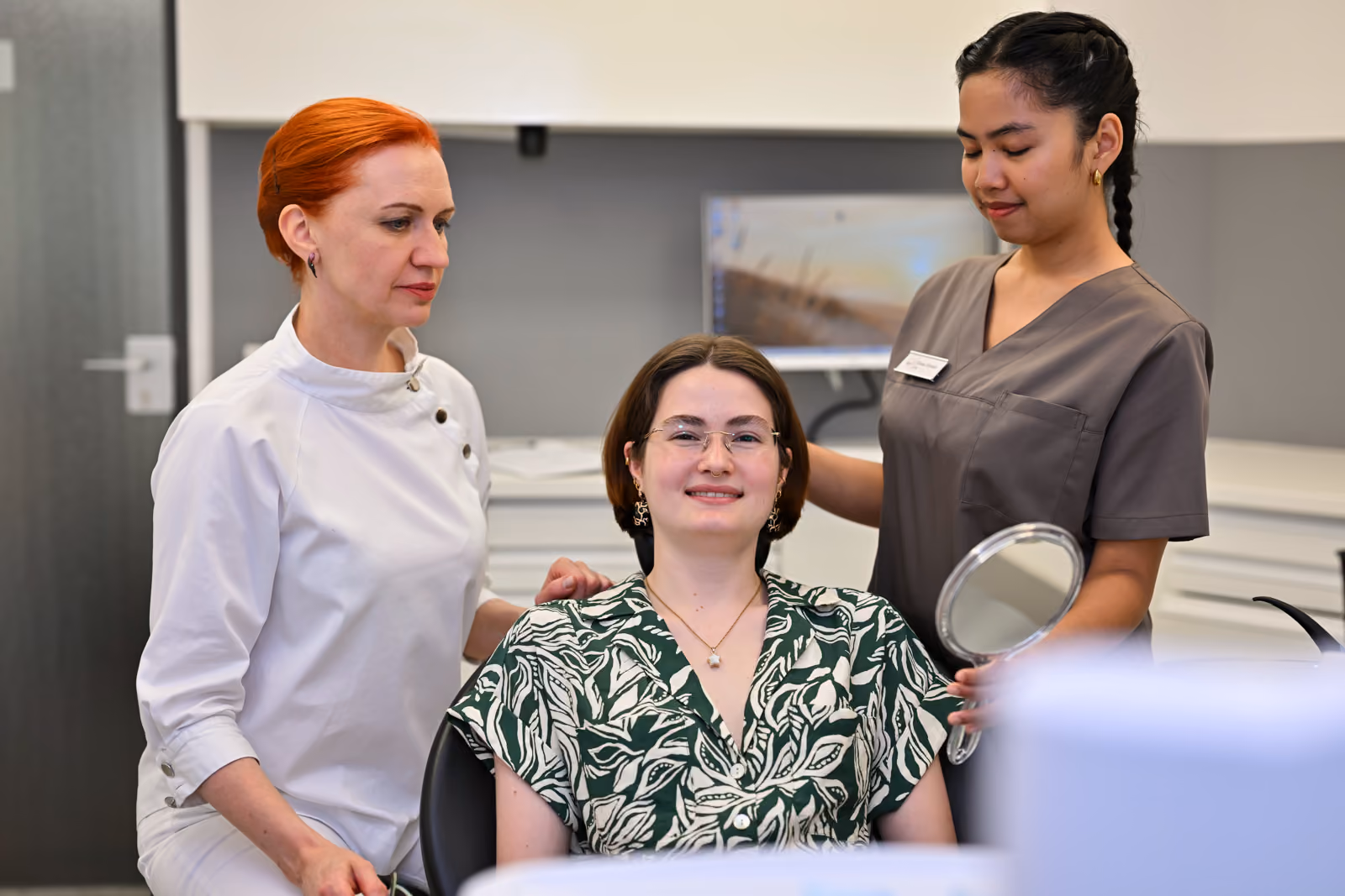 Dr. Elena Hartmann im Gespräch mit einer Patientin, daneben ihre Assistentin
