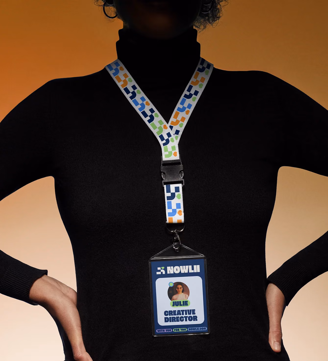 Nowlii-branded lanyard and ID badge worn by a person in silhouette, reading "Julie, Creative Director."