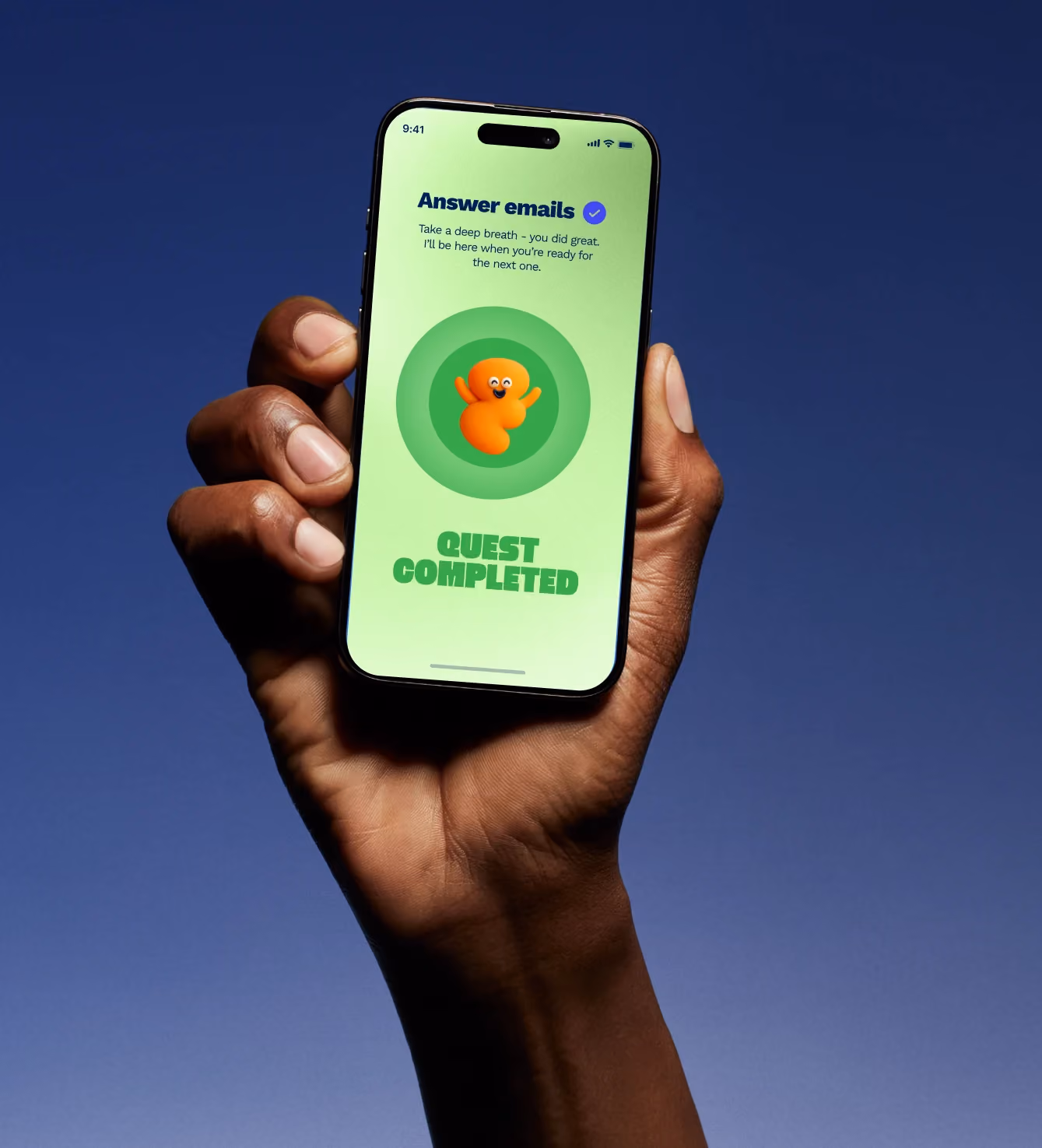 Hand holding a phone displaying a "Quest Completed" screen with the orange mascot.