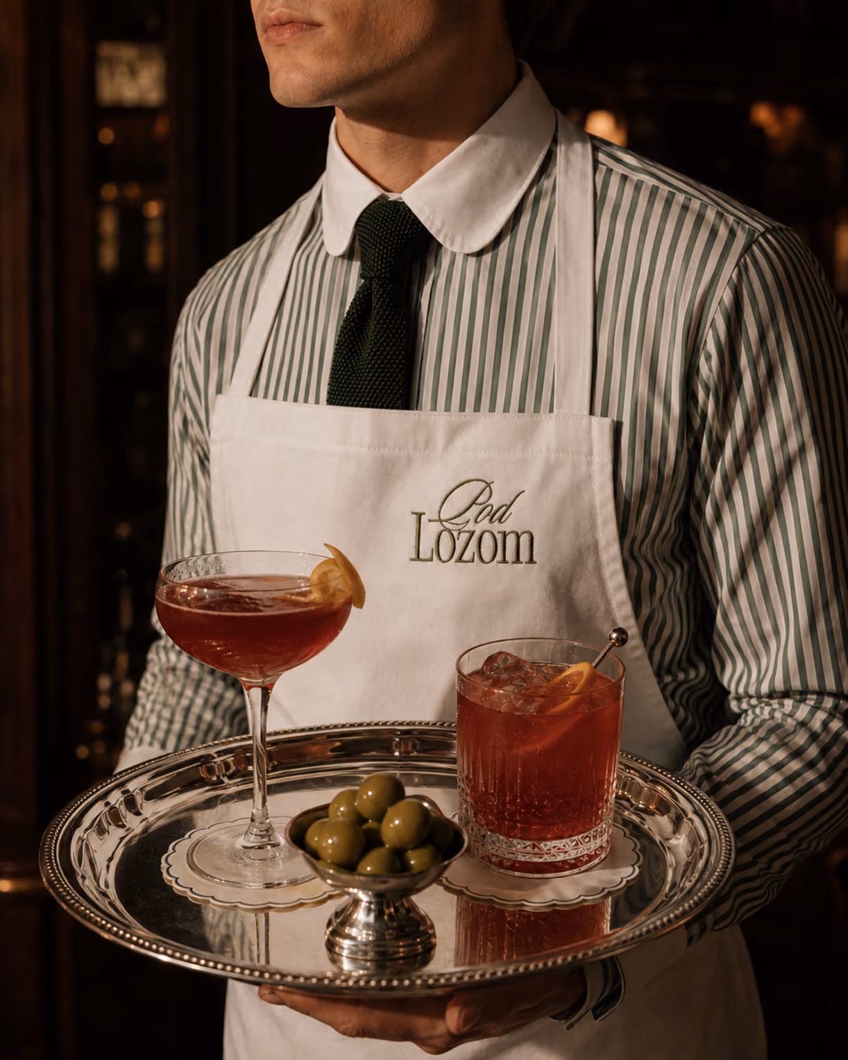Waiter holding a tray of cocktails and olives.