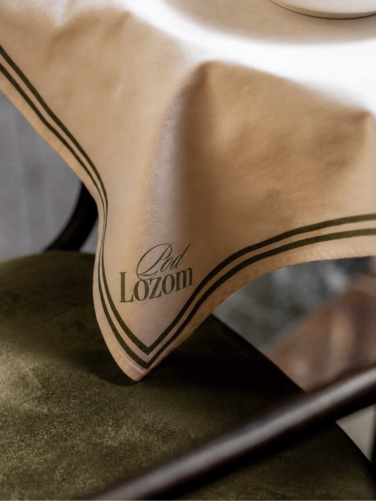 Close-up of Pod Lozom branded tablecloth on a chair.