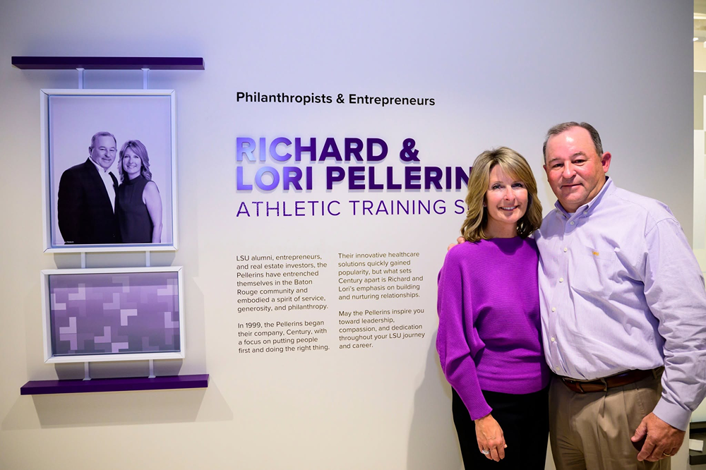 People standing beside the Richard and Lori Pellerin Athletic Training display.