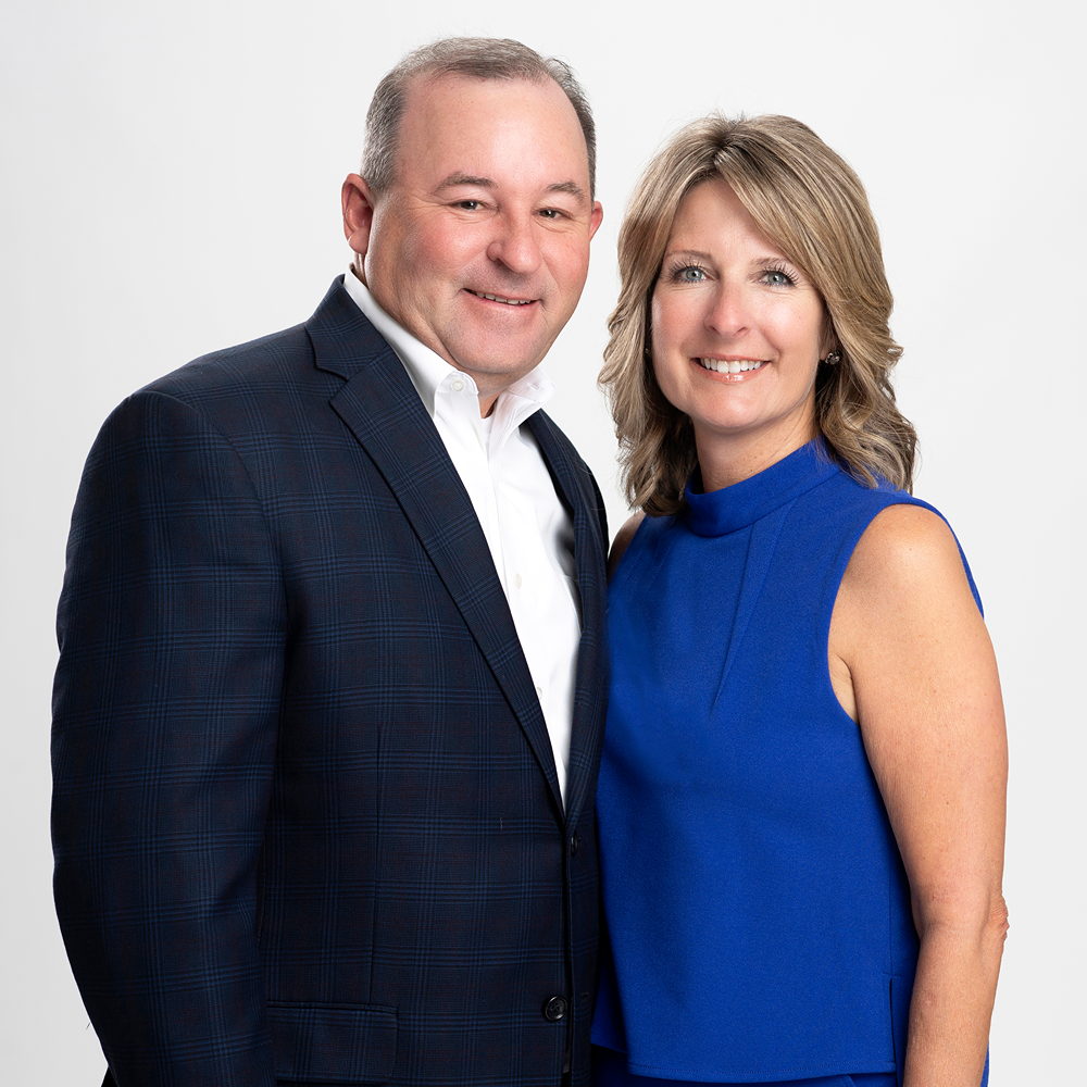 Professional portrait of a man in a dark suit and a woman in a blue dress.