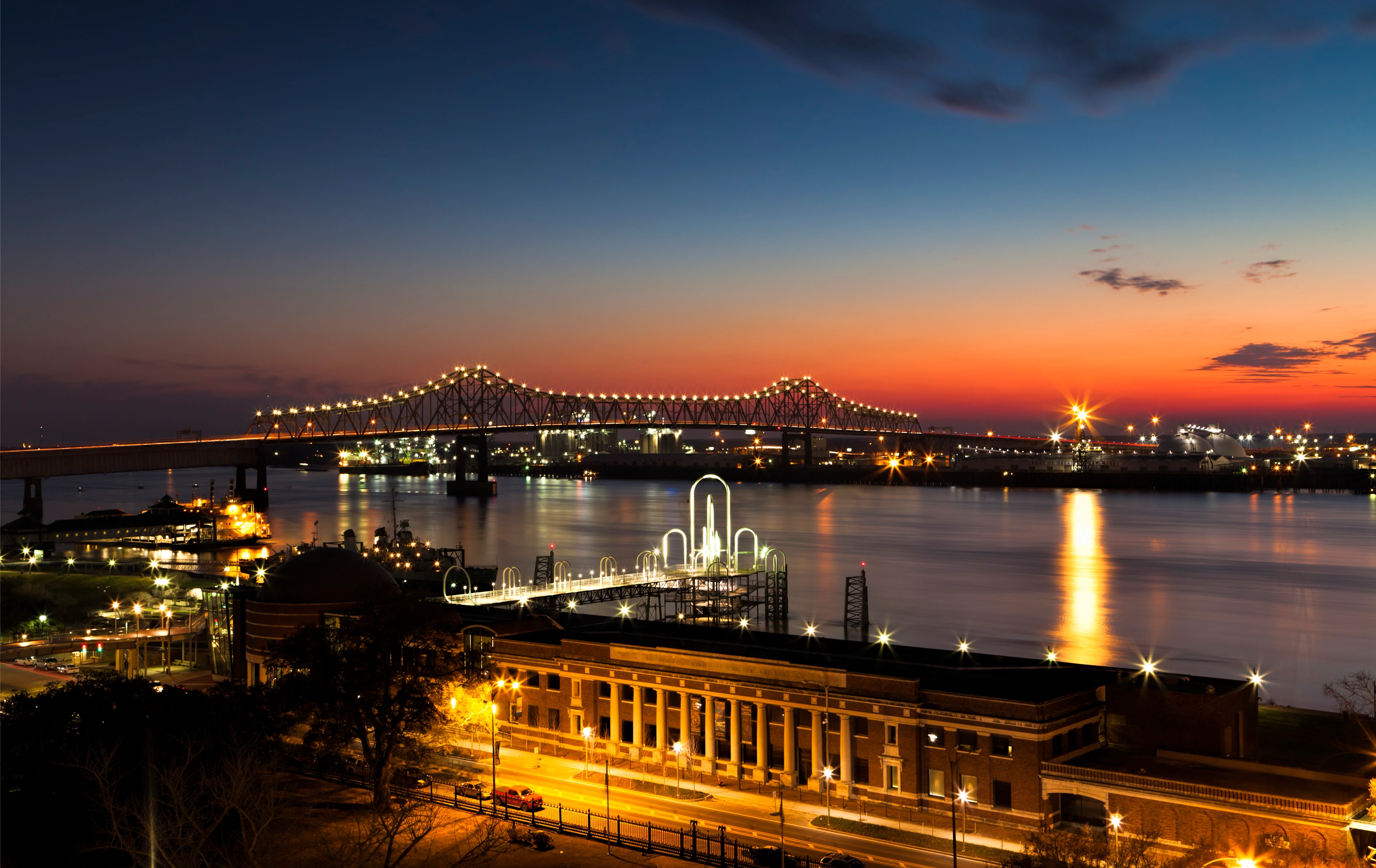 City skyline and bridge at sunset over a river.