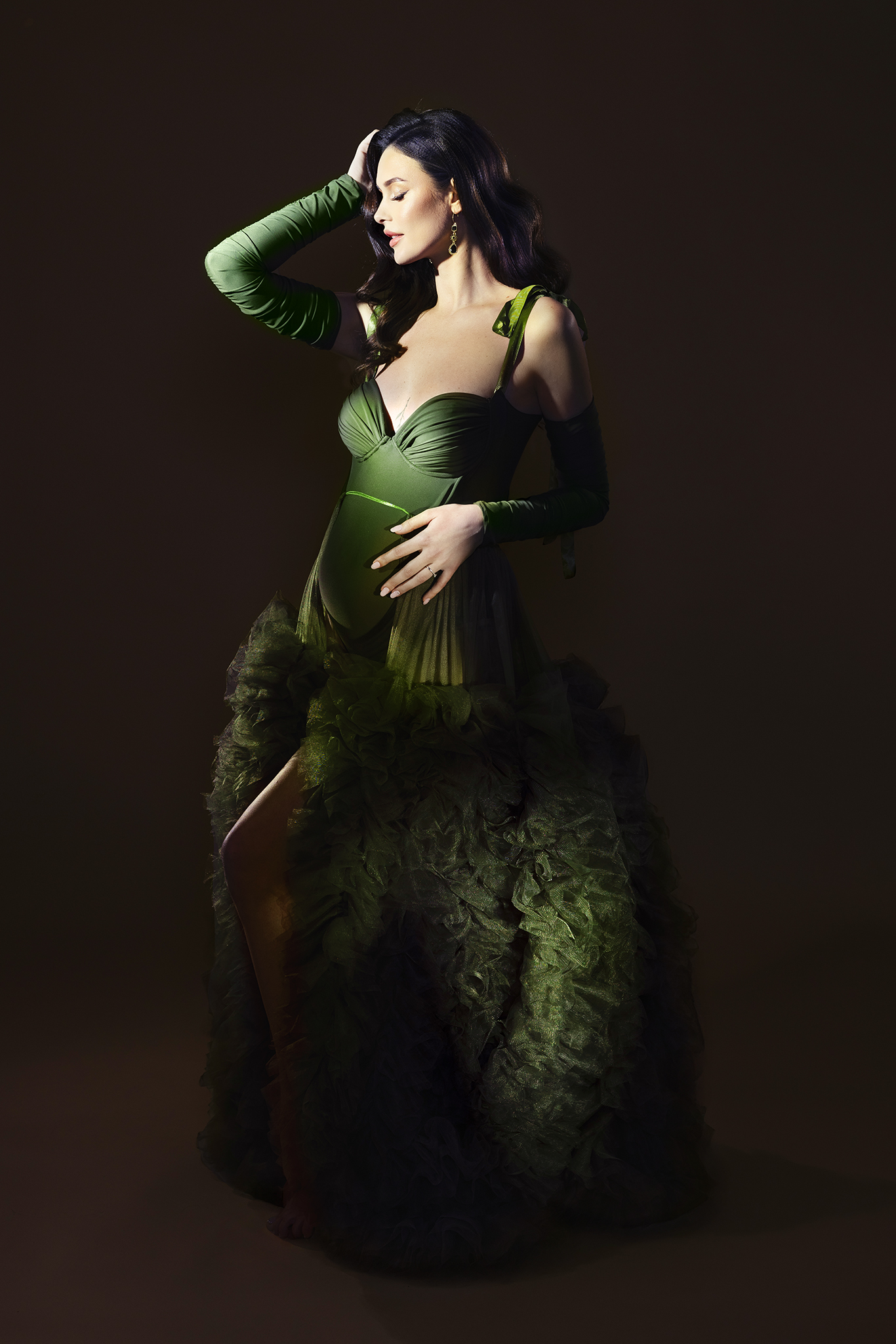 OPERA by Claudia Spaziani – produzione fotografica di maternità fine art a Bologna: donna incinta in abito verde smeraldo con corpetto strutturato e tulle voluminoso, mondo scenografico costruito da zero