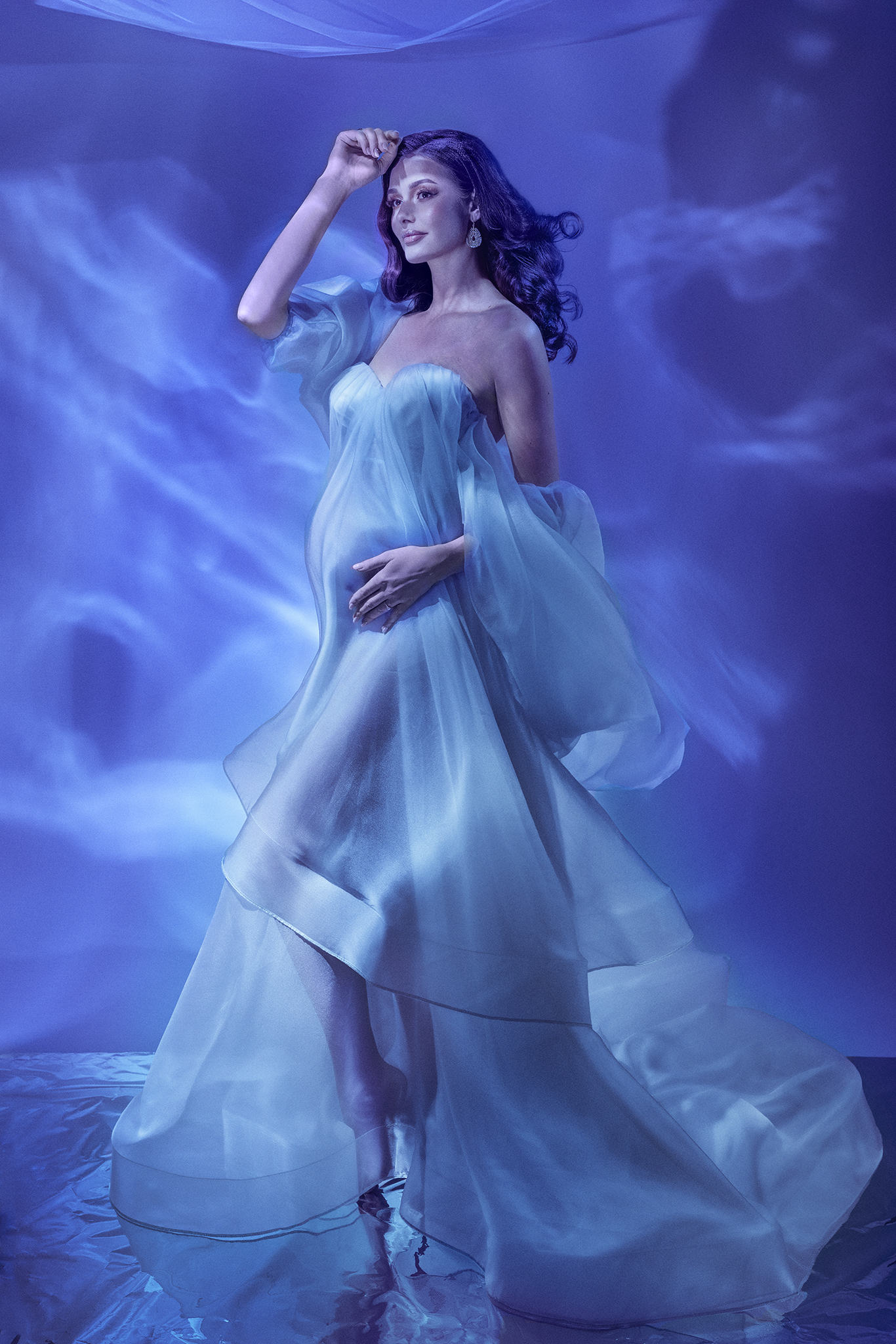OPERA by Claudia Spaziani – fotografia di maternità fine art a Bologna: donna incinta immersa in luci subacquee e organza azzurra, produzione esclusiva con effetti speciali e costumi da palcoscenico