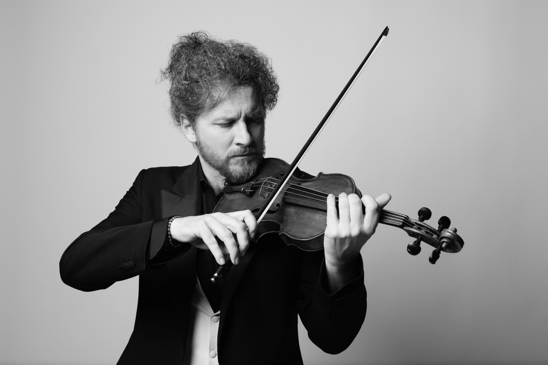 Marco, violinista, in bianco e nero mentre suona il violino con concentrazione intensa, ritratto fine art per book professionale di Claudia Spaziani a Bologna.