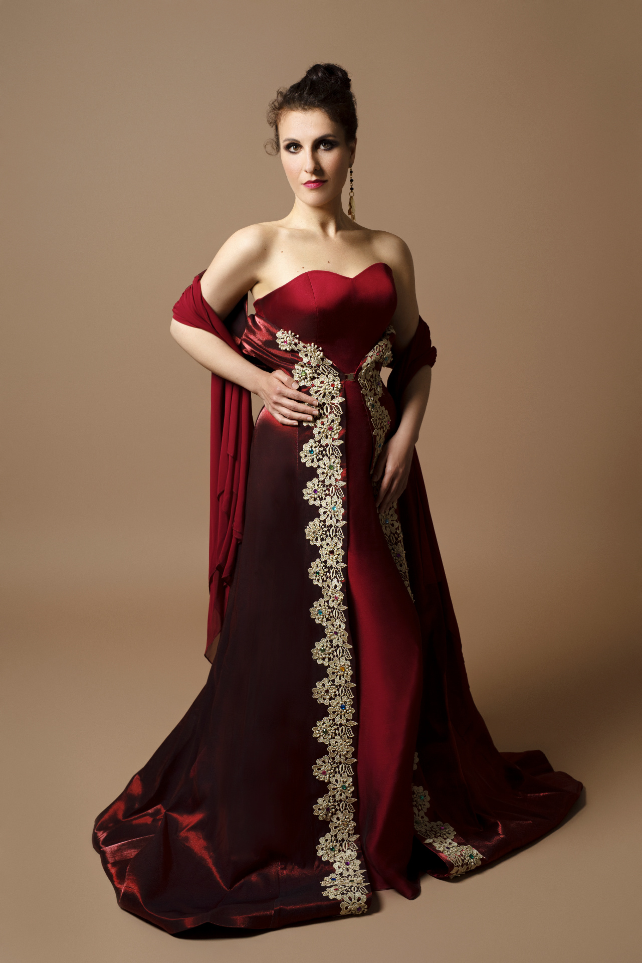 Soprano in abito da sera bordeaux con ricami dorati e strascico, ritratto elegante per book professionale di cantante lirica di Claudia Spaziani a Castel Guelfo, Bologna.