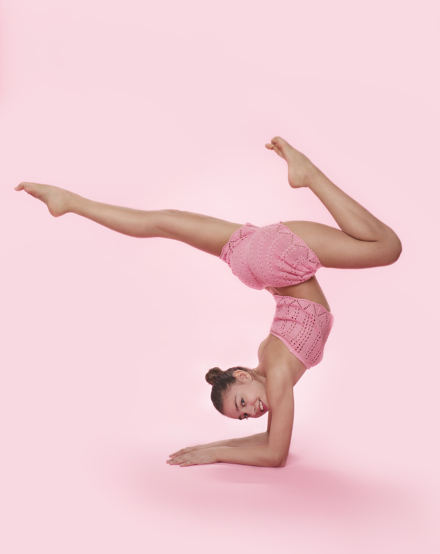 Ginnasta in outfit rosa in verticale laterale con gambe aperte e sguardo in camera, ritratto fine art di Claudia Spaziani a Castel Guelfo, Bologna.