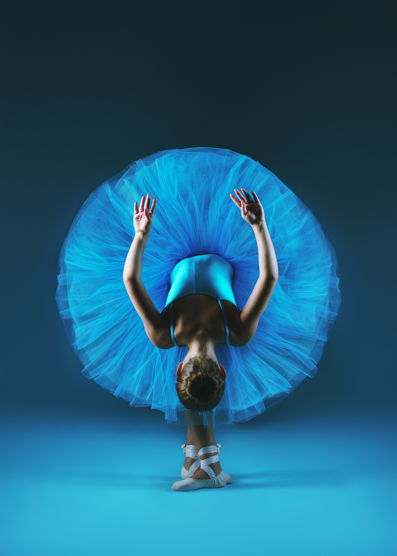 Ballerina in tutù azzurro visto di spalle in posa arcuata con braccia sollevate e scarpette da punta, ritratto fine art di Claudia Spaziani a Bologna.