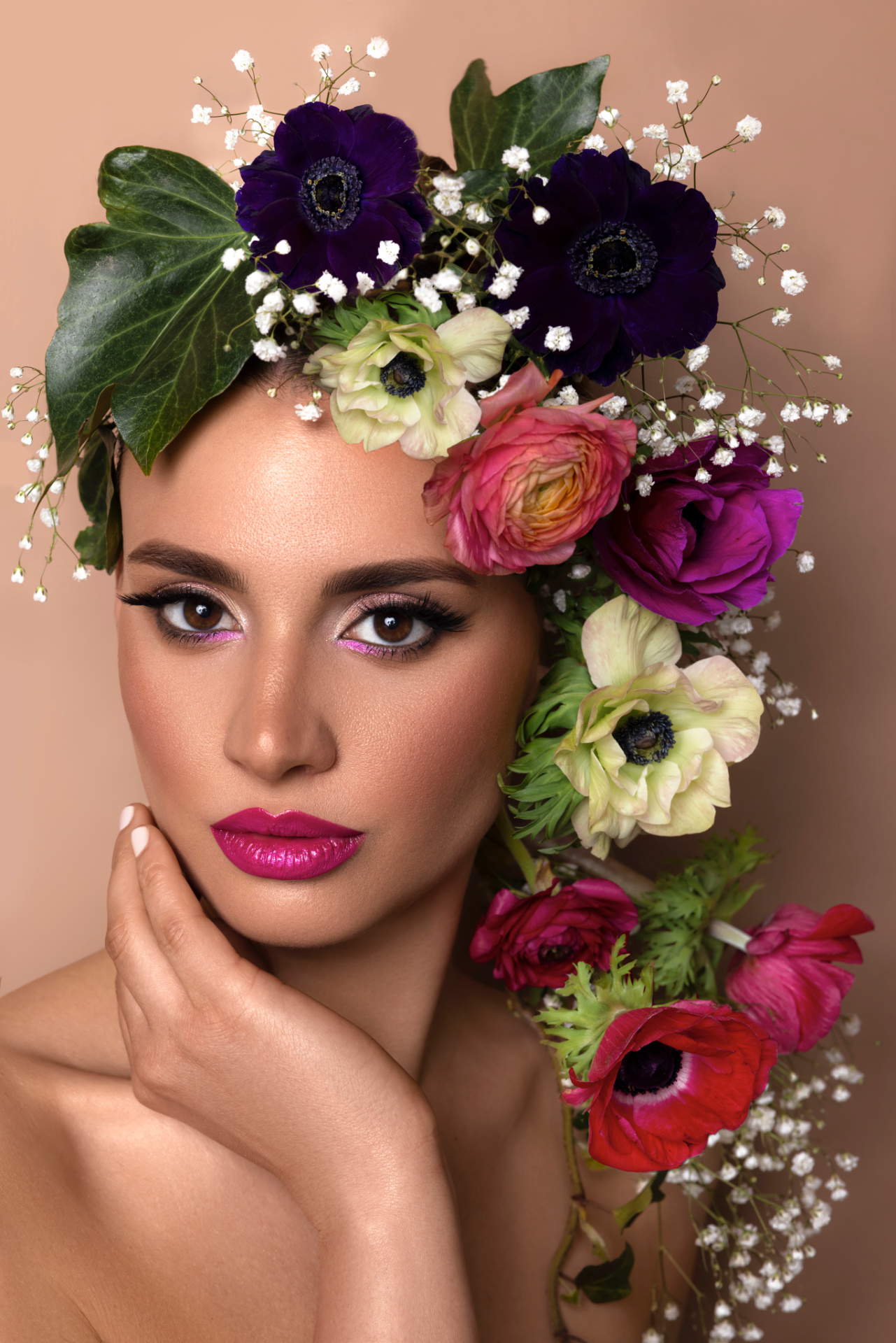Ritratto beauty fine art realizzato da Claudia Spaziani nel suo studio vicino a Bologna; styling floreale elaborato, trucco intenso e posa elegante su sfondo neutro.
