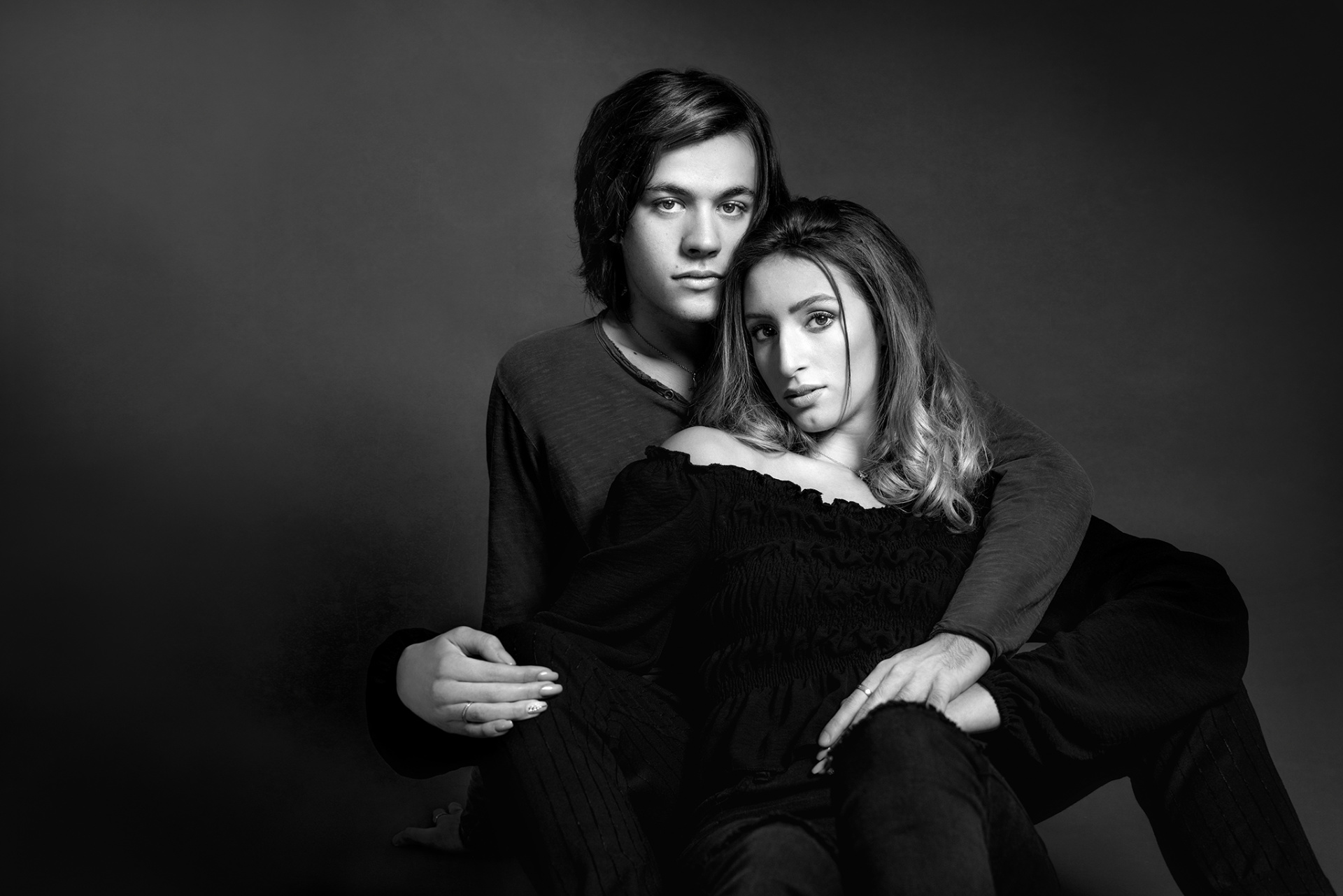 Ritratto artistico in bianco e nero di una coppia abbracciata, realizzato da Claudia Spaziani nel suo studio fotografico a Bologna. Composizione intima su sfondo scuro, con luce morbida che valorizza l’espressione e la connessione emotiva tra i due partner.
