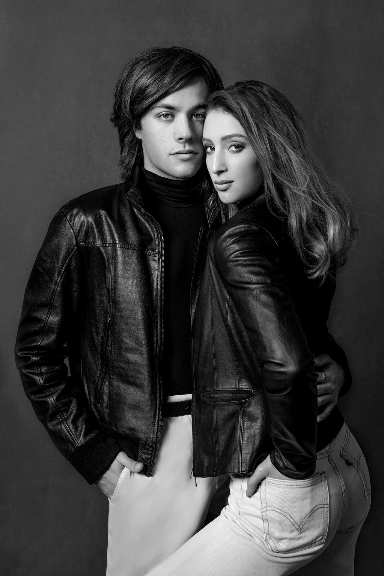 Ritratto in bianco e nero di una coppia con giacche in pelle, scattato da Claudia Spaziani nel suo studio fotografico a Bologna. Posa ravvicinata e abbigliamento elegante su sfondo scuro, che trasmette stile e intimità.