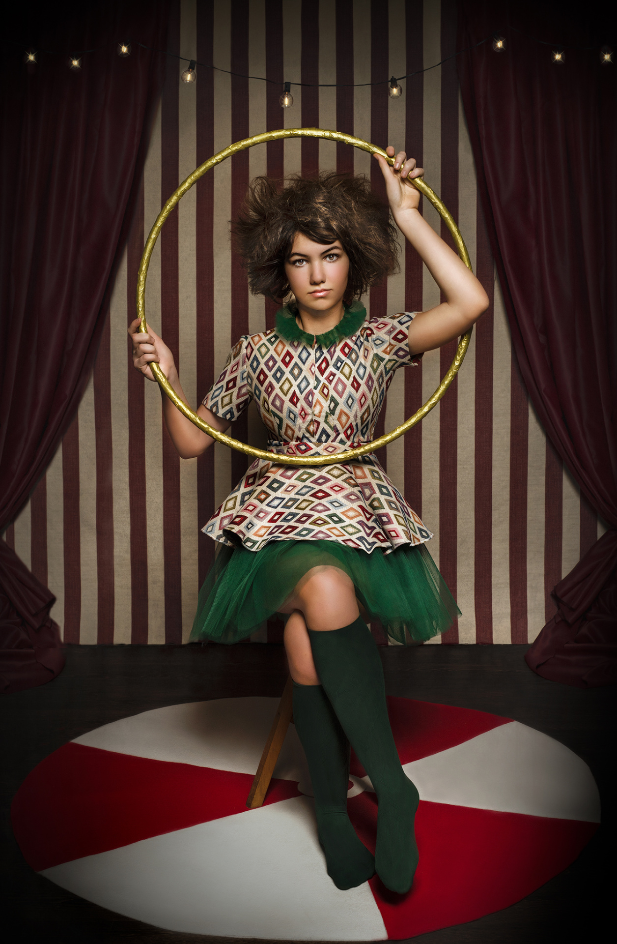 Ritratto creativo in stile vintage circus con persona seduta su sgabello e cerchio dorato, ambientato in un set teatrale.
