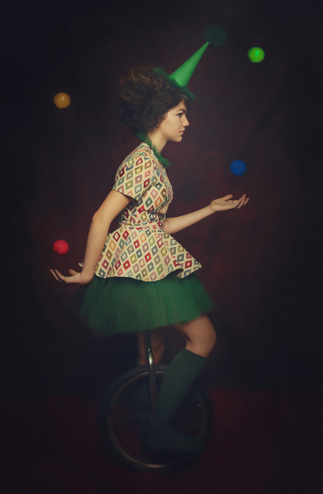 Ritratto teatrale di artista circense su monociclo che gioca con palline colorate, fotografato da Claudia Spaziani a Bologna.