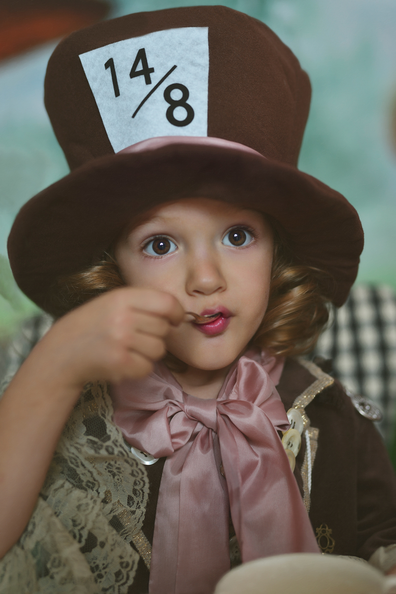 Scena giocosa con bambino vestito da Cappellaio Matto che mangia un dolcetto, fotografato in stile narrativo a Bologna.