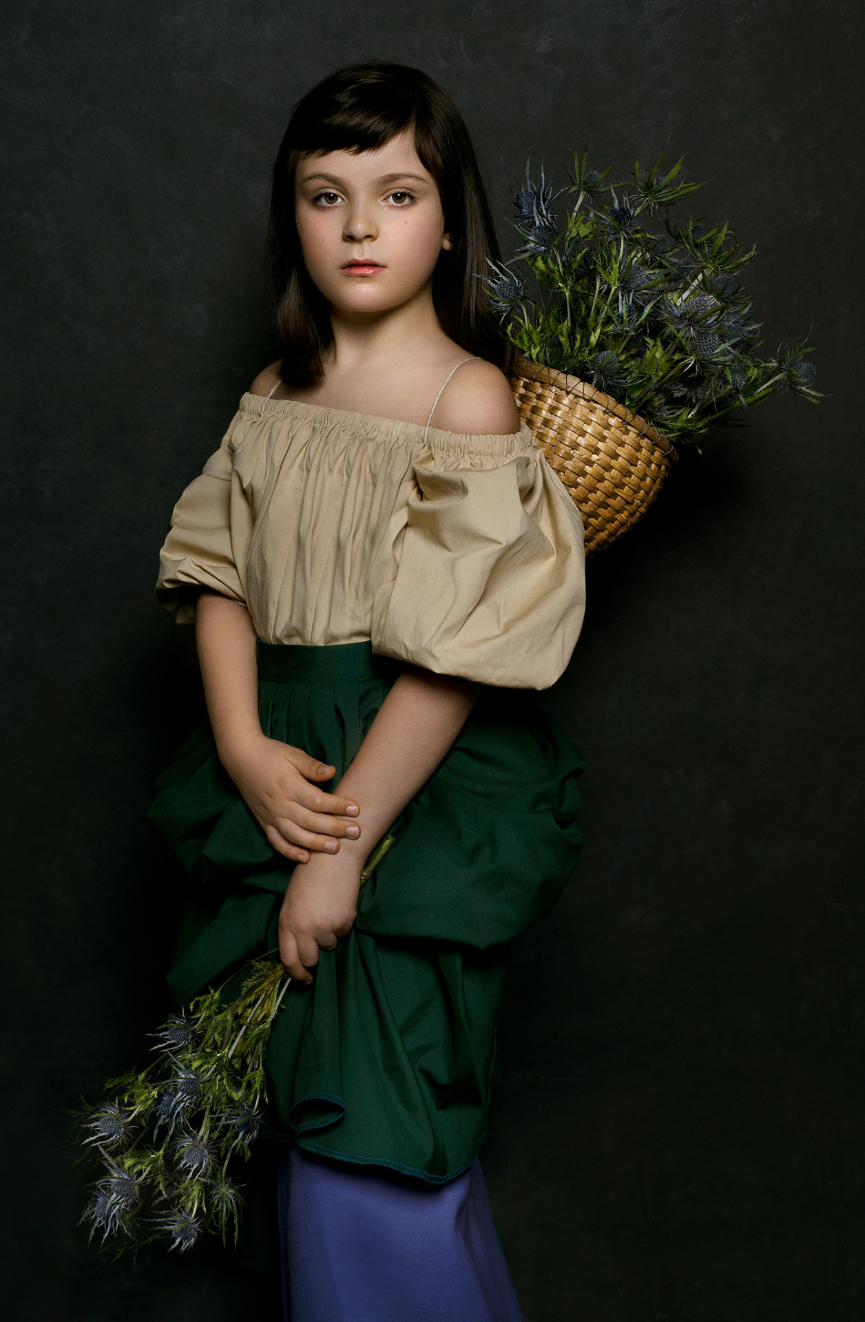 Ritratto evocativo di bambina in abito tradizionale con mazzo di cardi e cesta floreale, realizzato da Claudia Spaziani a Bologna.