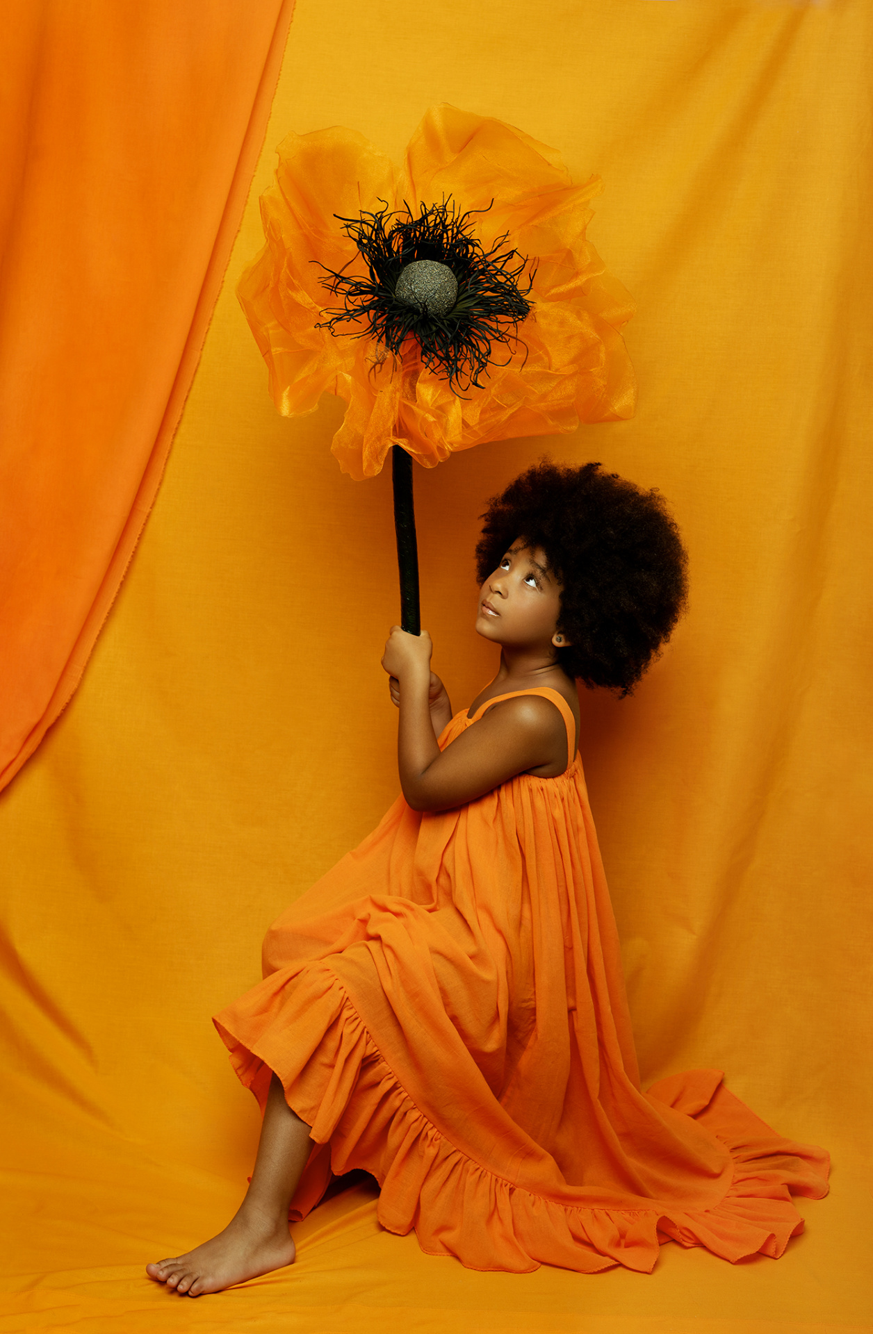 Ritratto monocromatico di bambina in abito arancione con fiore stilizzato, su sfondo arancio, realizzato da Claudia Spaziani a Bologna.