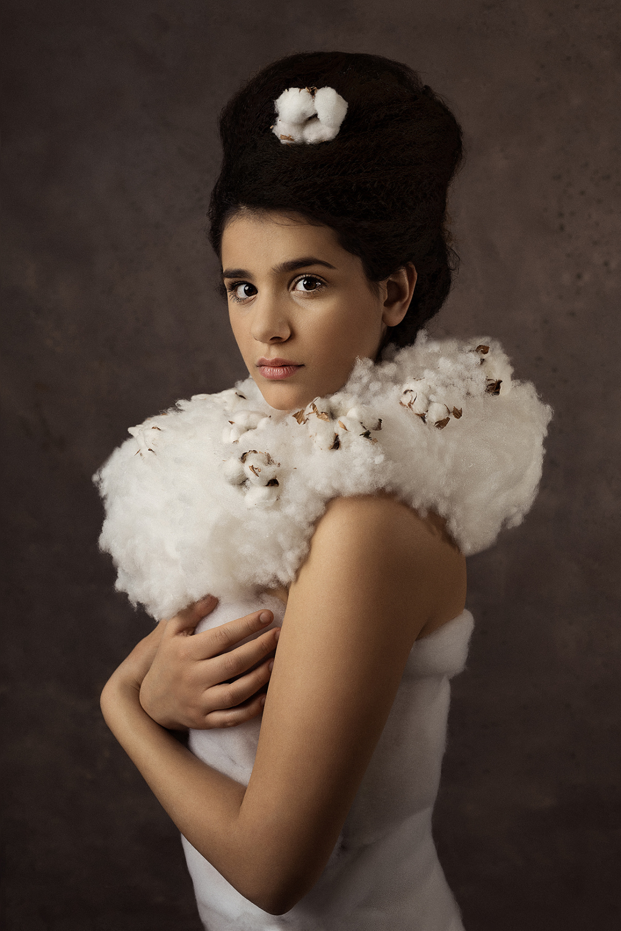 Ritratto fine-art di adolescente in abito voluminoso di cotone con acconciatura elaborata, scattato da Claudia Spaziani nel suo studio fotografico a Bologna.