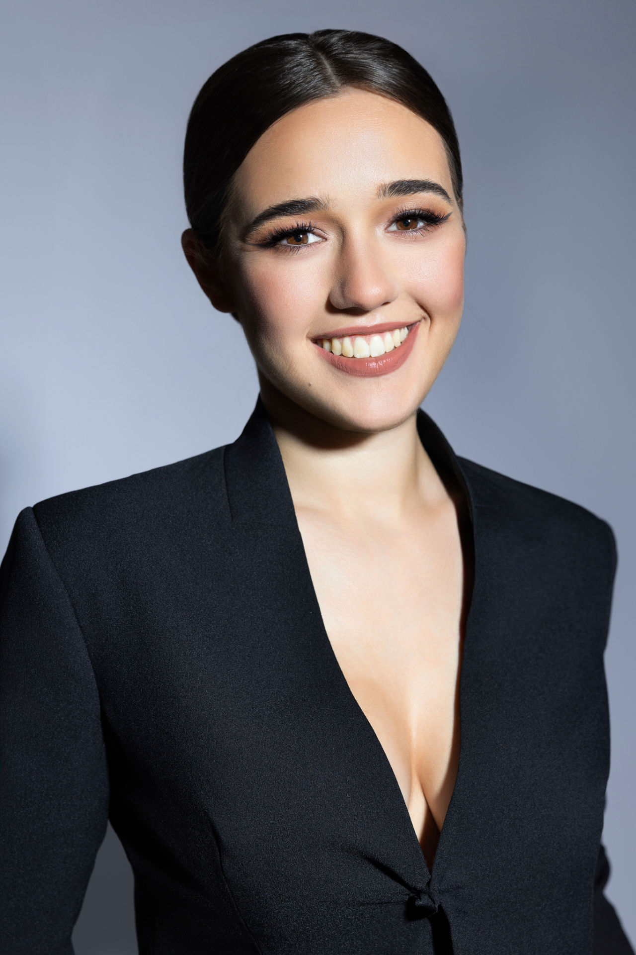 Ritratto professionale di adolescente in abito nero con scollo profondo e sorriso luminoso, realizzato da Claudia Spaziani nel suo studio fotografico a Bologna.