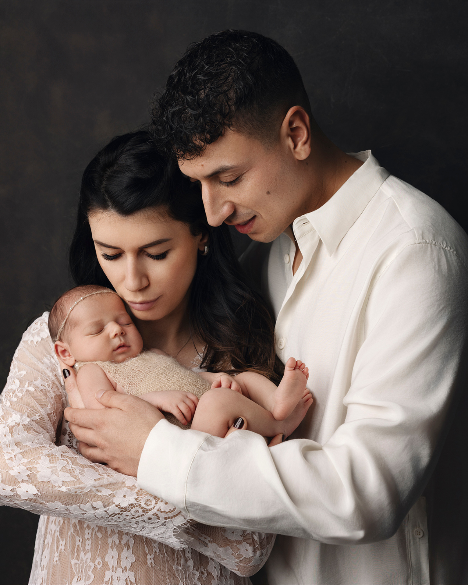 Foto di famiglia con neonata femmina addormentata, realizzata da Claudia Spaziani fotografa a Bologna. Immagine intima e affettuosa che celebra amore e legame familiare.