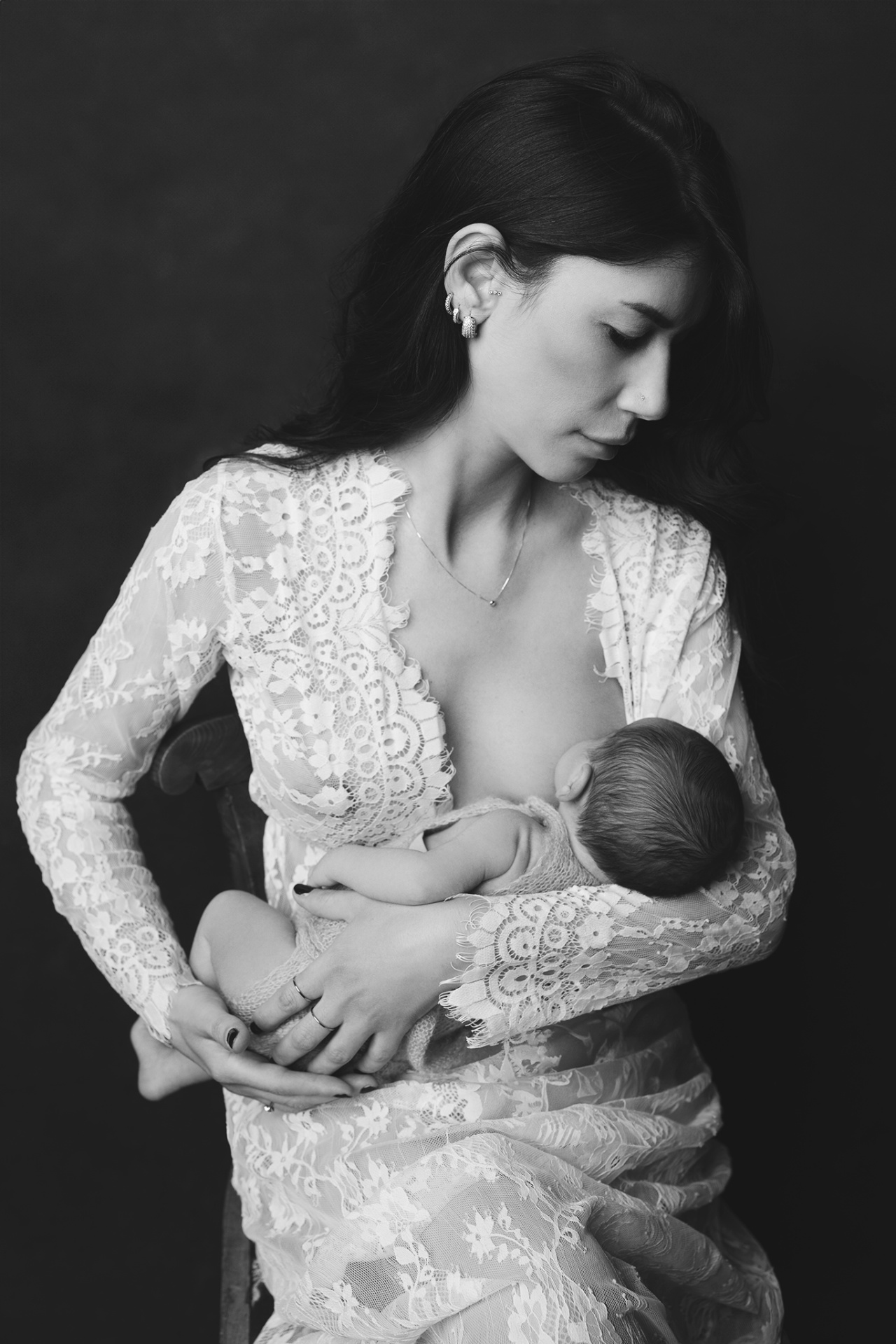 Ritratto artistico in bianco e nero di madre che allatta la neonata, realizzato nello studio fotografico di Claudia Spaziani a Bologna. Immagine intima e senza tempo che celebra maternità e legame.