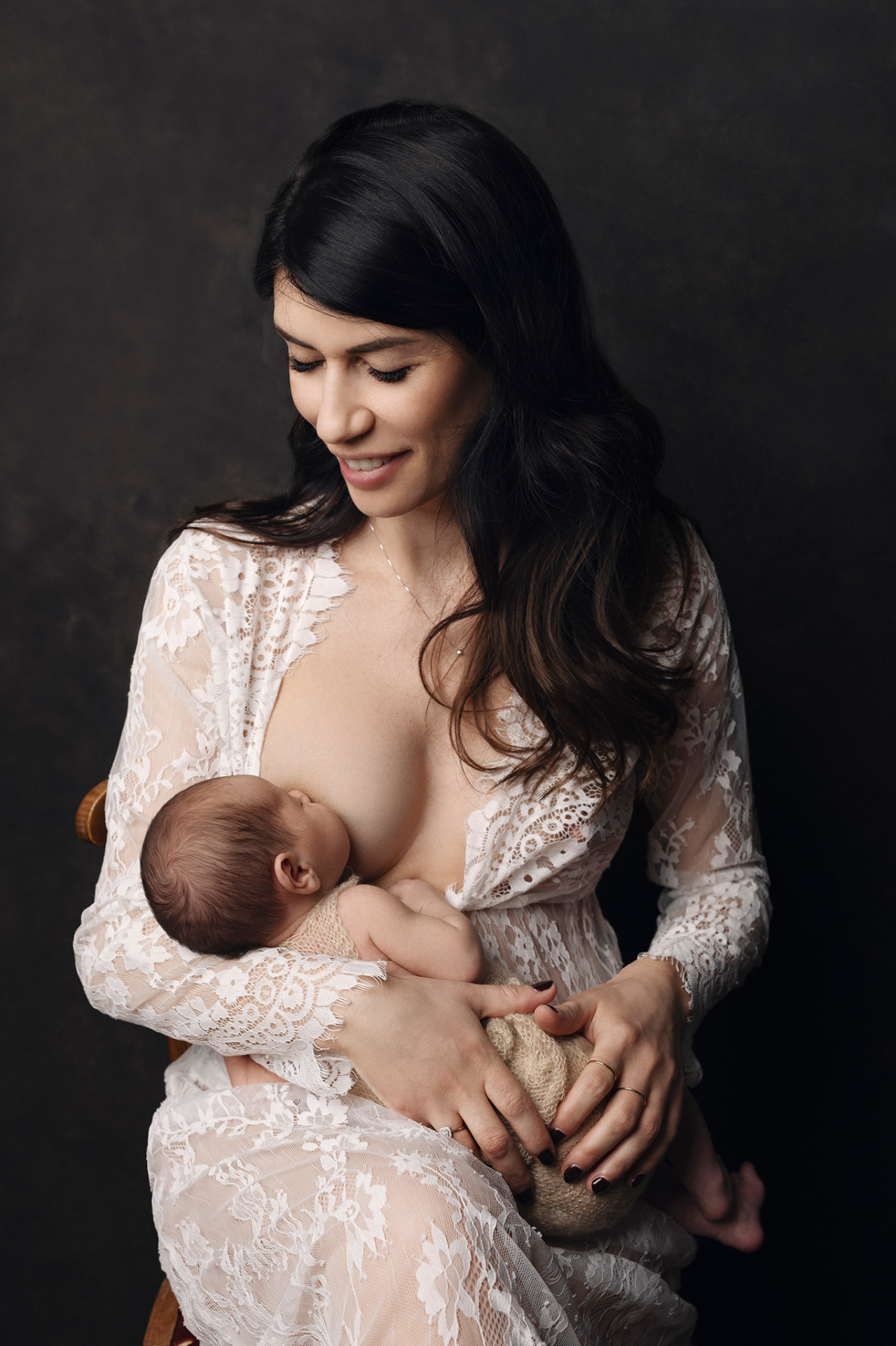 Foto intima di madre che allatta neonata femmina, scattata nello studio di Claudia Spaziani a Bologna. Immagine che celebra maternità e legame affettuoso.