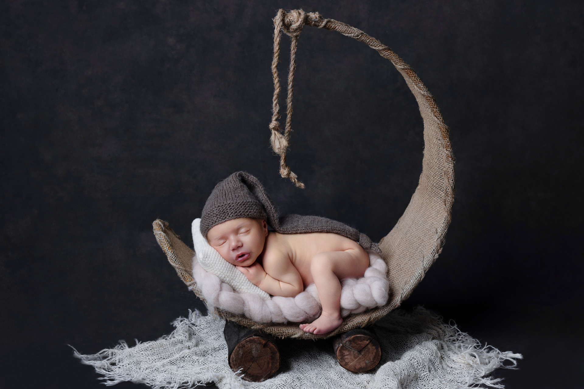 Ritratto creativo di neonato maschio addormentato su culla a forma di luna, fotografato nello studio di Claudia Spaziani a Bologna. Immagine fiabesca e suggestiva.