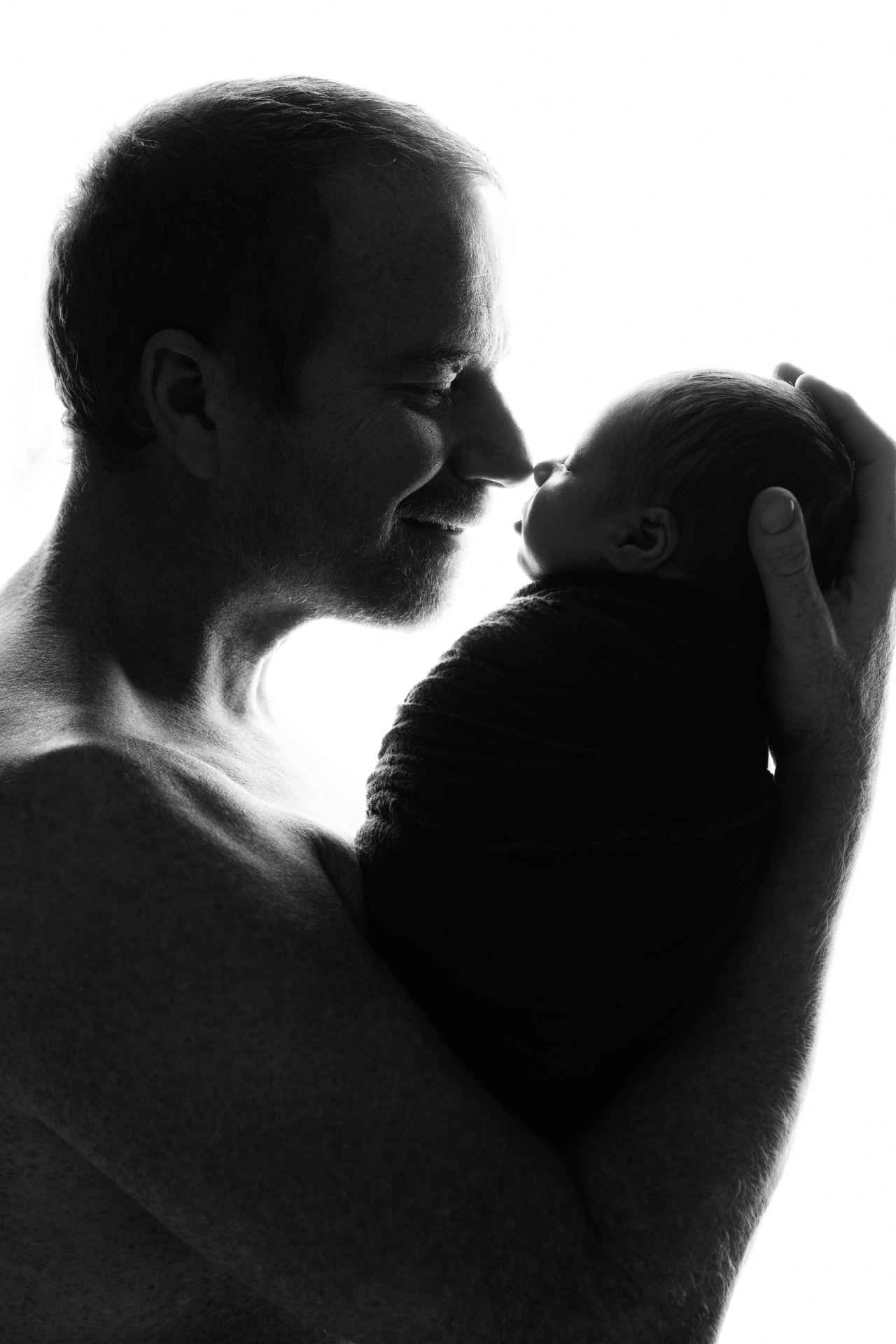 Ritratto in bianco e nero di padre che culla la neonata addormentata, realizzato da Claudia Spaziani fotografa a Bologna. Fotografia che esalta amore e protezione.