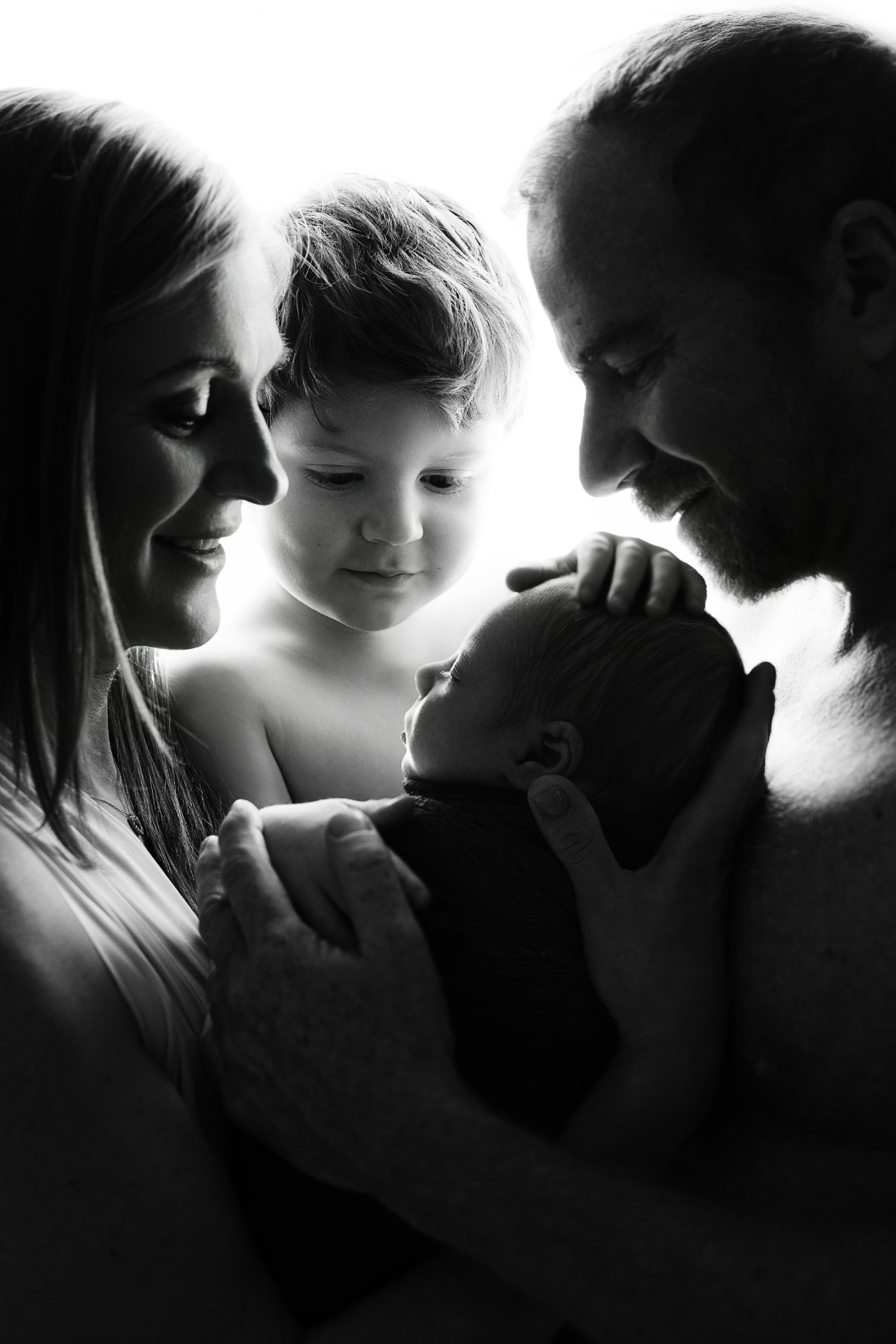 Foto in bianco e nero di famiglia con neonato maschio e fratello maggiore, realizzata nello studio di Claudia Spaziani a Bologna. Immagine che esalta amore e connessione.