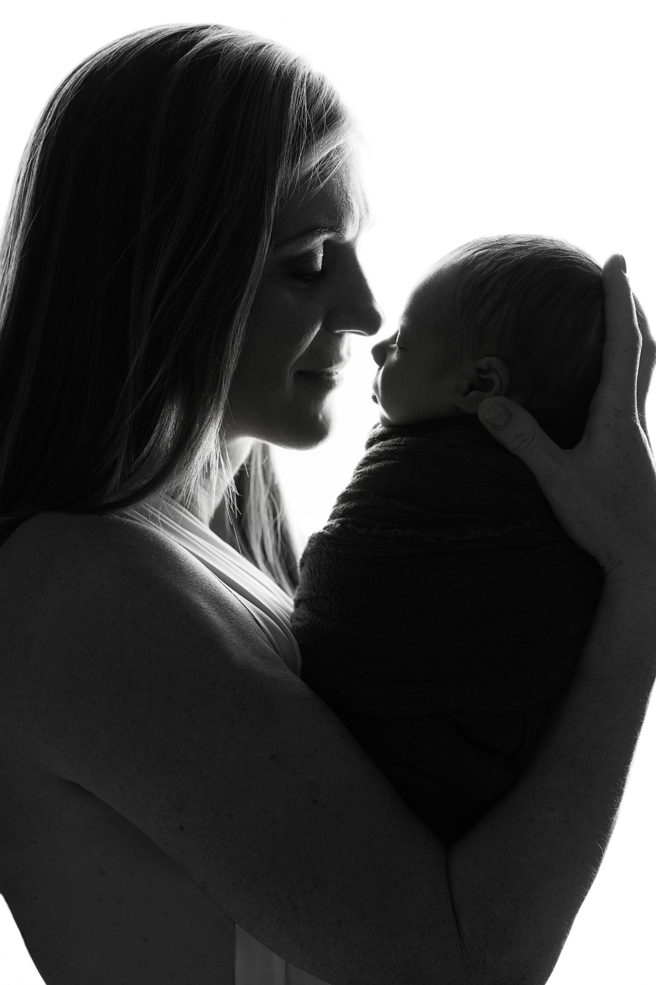 Foto artistica in bianco e nero in silhouette di madre che culla neonato maschio, realizzata da Claudia Spaziani fotografa a Bologna. Immagine intima e suggestiva.